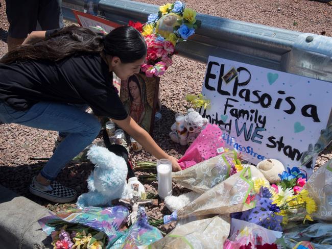 A woman places flowers beside a makeshift memorial outside the Cielo Vista Mall Walmart (background) where a shooting left 22 people dead in El Paso, Texas. Picture: AFP