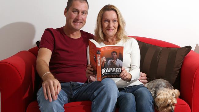 Marcus and Julie Lee at their Burleigh Waters home with dog Dudley and their new book <i>Trapped</i>. Pic: Glenn Hampson