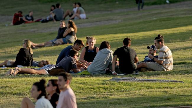 Groups of people sit on the grass at the south end of a closed Bondi Beach on Saturday. Picture: Damian Shaw