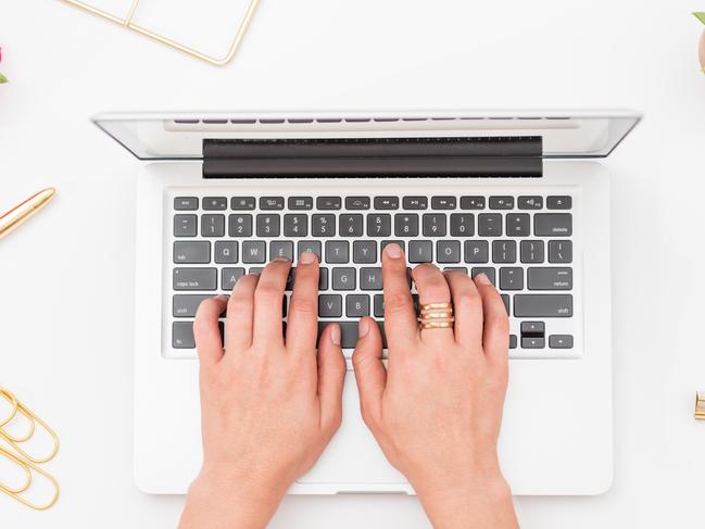 A woman working at a laptop on a desk. Conveys the idea of a blogger or influencer working from home.