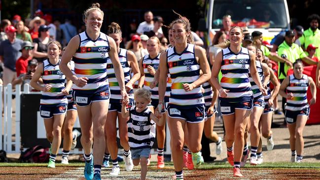 Kate Darby with daughter Ella and Georgie Rankin lead Geelong out against Sydney to mark their 50th games. Picture: Brendon Thorne/AFL Photos/via Getty Images