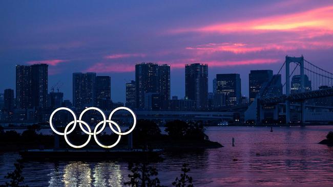 A general view shows the Olympic rings lit up at dusk, with the Rainbow bridge in the background, on the Odaiba waterfront in Tokyo. Picture: AFP