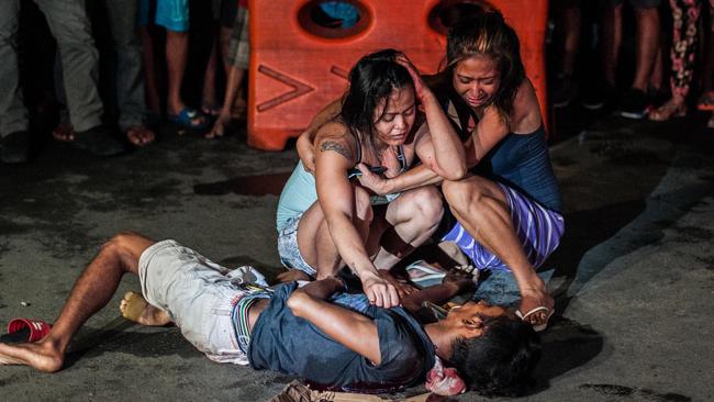 Two women weep over the body of an alleged drug peddler shot in a main thoroughfare in Manila. Picture: Getty Images