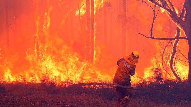 A firefighter struggles to contain the blaze on a threatened property.