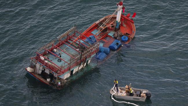 Workers attempt to stem the flow of diesel from the vessel. Picture: Marc McCormack