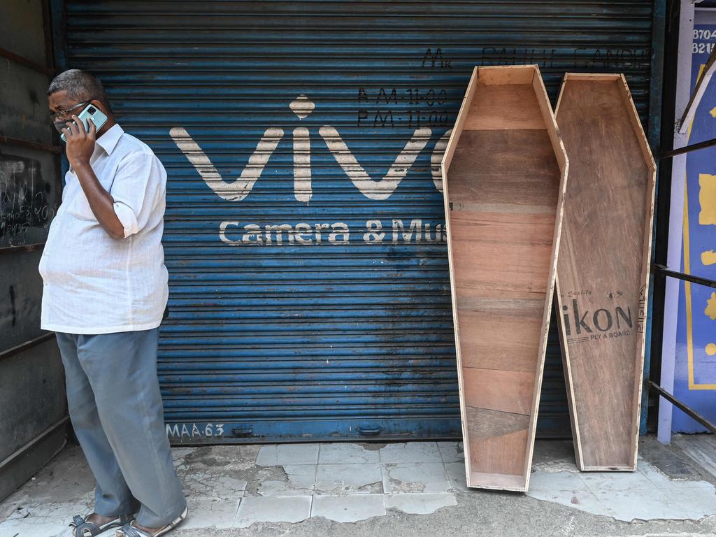 A man talks on his mobile phone while standing next to an unfinished coffin outside an undertaker’s shop in Mumbai. Picture: Indranil Mukherjee