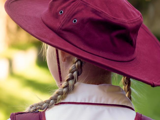 A girl wearing school uniform, white shirt, maroon backpack and maroon hat Back to school. Return to classrooms after COVID-19 outbreak in Australia