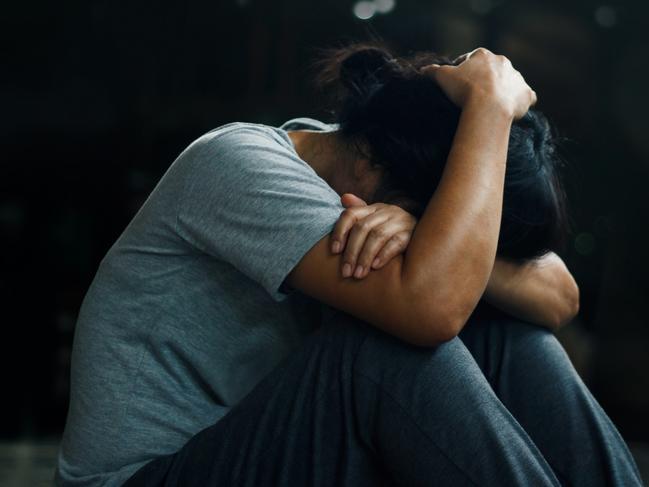 PTSD Mental health concept. Post Traumatic Stress Disorder. The depressed woman sitting alone on the floor in the dark room background. Film look. Picture: iStock