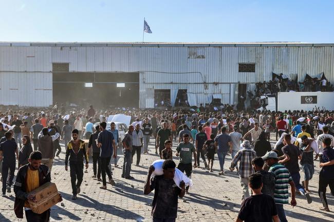 Displaced Palestinians ferry bags of food aid after storming a World Food Programme warehouse in Deir el-Balah in the central Gaza Strip on May 28, 2025