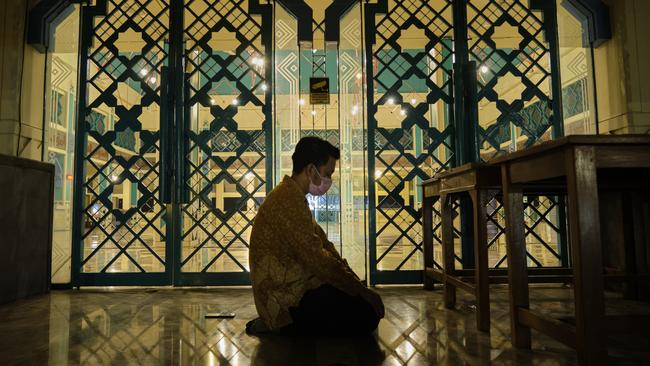 Rizky Riansy prays outside a closed mosque his Jakarta neighbourhood after finishing work. Picture: Ed Wray