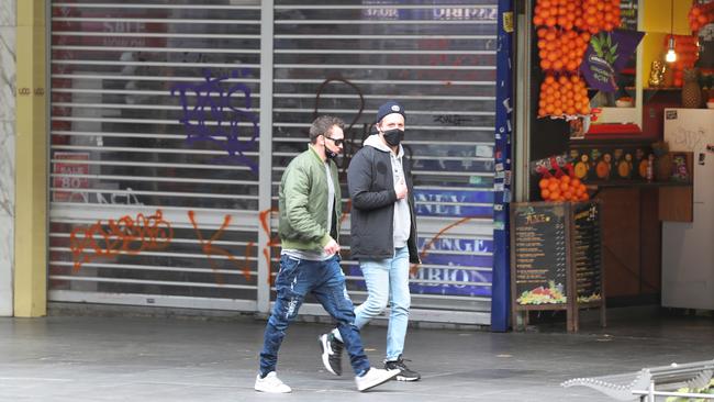 Pedestrians walks along a mostly-closed Swanston street during day one of the stage four lockdown in Melbourne. Picture: NCA NewsWire / David Crosling