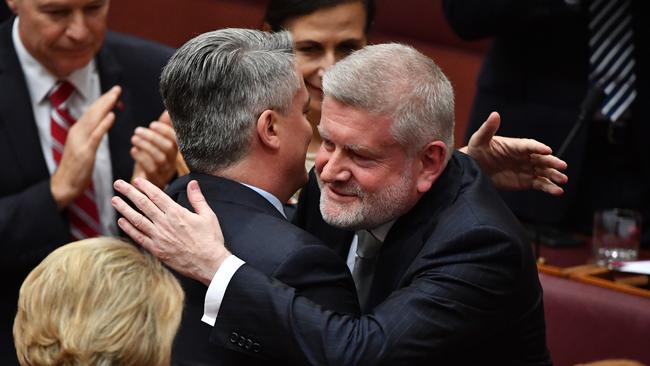 Minister for Finance Mathias Cormann hugs Liberal Senator Mitch Fifield after making his valedictory speech in the Senate chamber. Picture: AAP