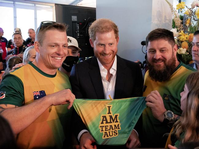 Invictus Games Team Australia competitors Matt Model (L) and Damien Irish (R) gift a pair of Team Australia swimmers to Prince Harry. Picture: AFP