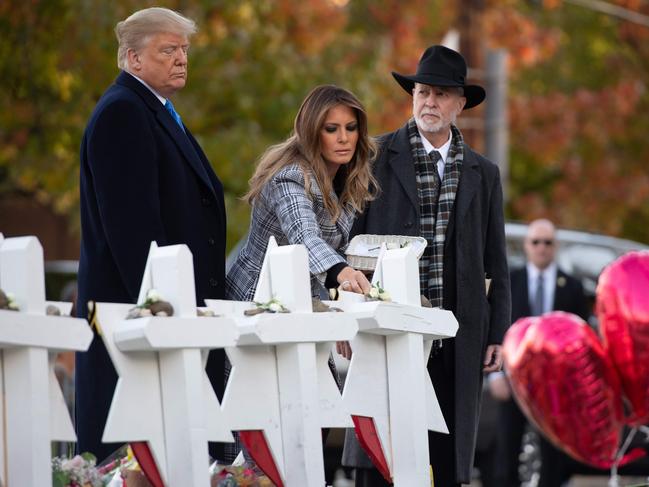 TOPSHOT - US President Donald Trump and First Lady Melania Trump, alongside Rabbi Jeffrey Myers, place stones and flowers on a memorial as they pay their respects at the Tree of Life Synagogue following last weekend's shooting in Pittsburgh, Pennsylvania, October 30, 2018. - Scores of protesters took to the streets of Pittsburgh to denounce a visit by US President Donald Trump in the wake of a mass shooting at a synagogue that left 11 people dead. Demonstrators gathered near the Tree of Life synagogue, where the shooting took place, holding signs that read 