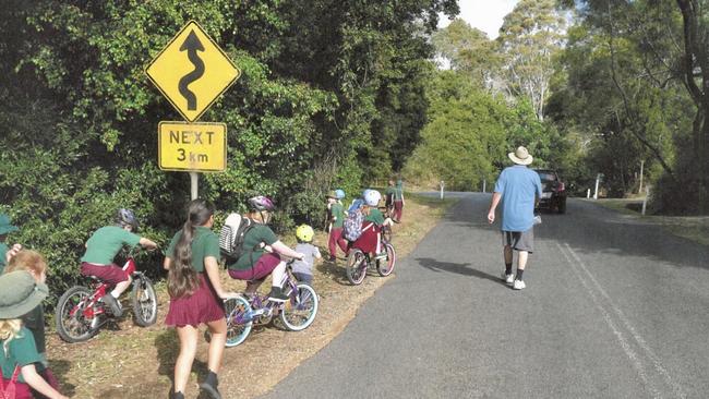 Parents check on children leaving school along a busy stretch of hinterland road at Springbrook which lacks a footpath.