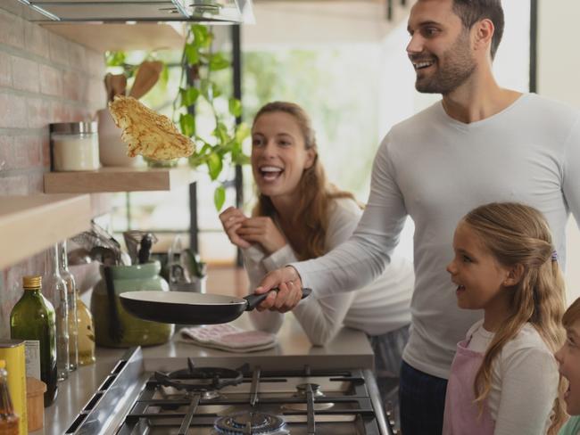 Front view of happy Caucasian family preparing food in kitchen in a comfortable home