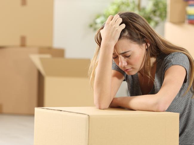 Sad homeowner moving home after eviction sitting on the floor of the living room at home