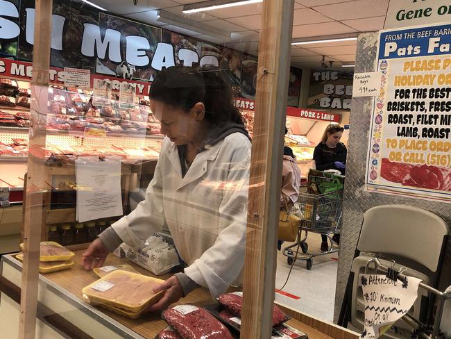 A grocery store cashier operates behind a glass barrier in New York. Picture: AFP