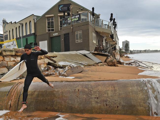 A surfer leaps past the ruined beach club. Picture: AFP