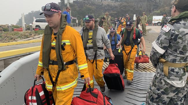 CFA volunteers board HMAS Choules landing craft as they depart Mallacoota.