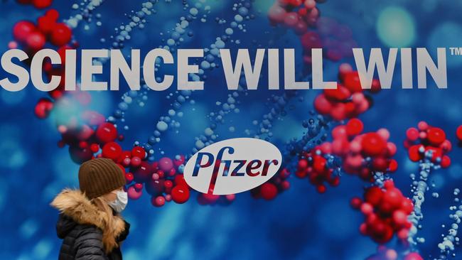 A person wearing a protective face mask walks past the Pfizer Inc. headquarters in New York City. Picture: AFP