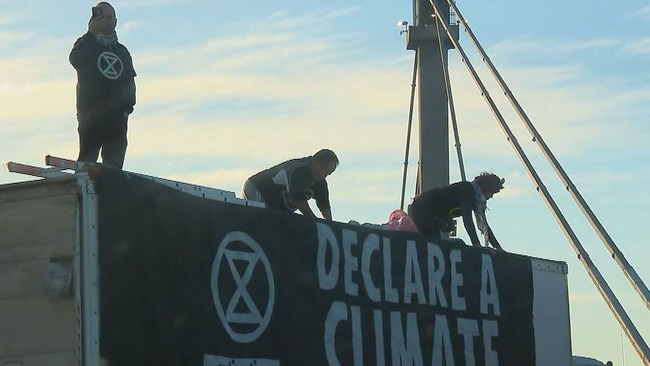 Extinction Rebellion protesters have once again disrupted traffic on a Melbourne Freeway. Sitting atop a truck wielding “business as usual = death” signs. Picture: 9NEWS