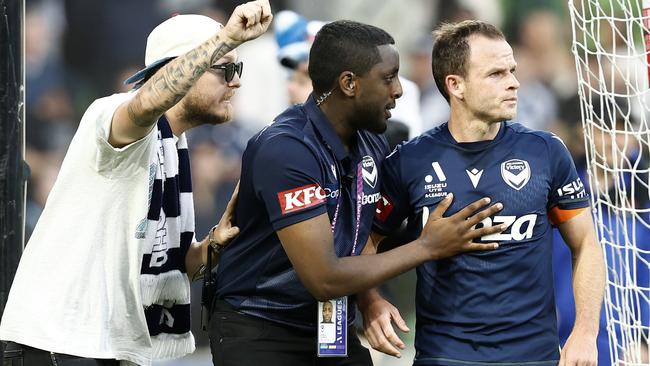 Leigh Broxham of Melbourne Victory is escorted from the pitch after fans stormed the ground. Picture: Darrian Traynor/Getty Images