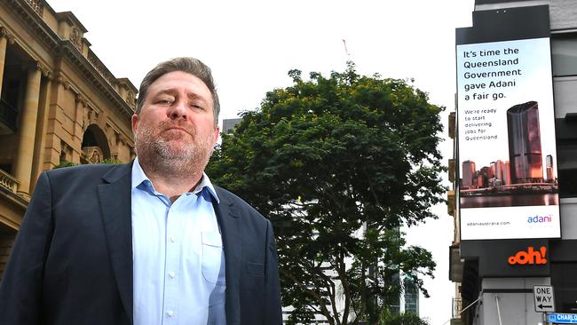 Adani Mining chief Lucas Dow with one of the mining giant’s billboards in Brisbane. Picture: AAP image/John Gass