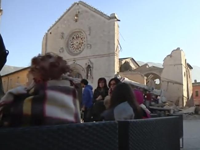 Residents who fled from their houses gather in a square in front of a damaged church in Norcia, Italy. Picture: Sky Italia via AP
