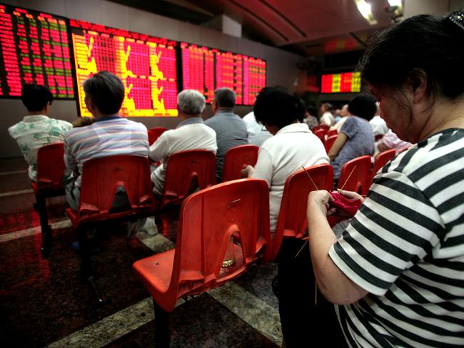 An investor knits while watching stock quotes at a securities trading firm in Shanghai on Thursday.