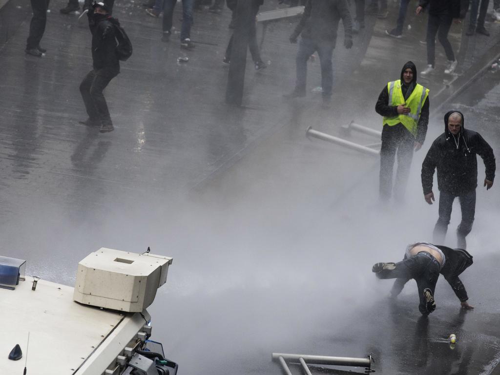 A protester is hit by a police water cannon during an anti-migrant demonstration outside of EU headquarters in Brussels. Picture: AP