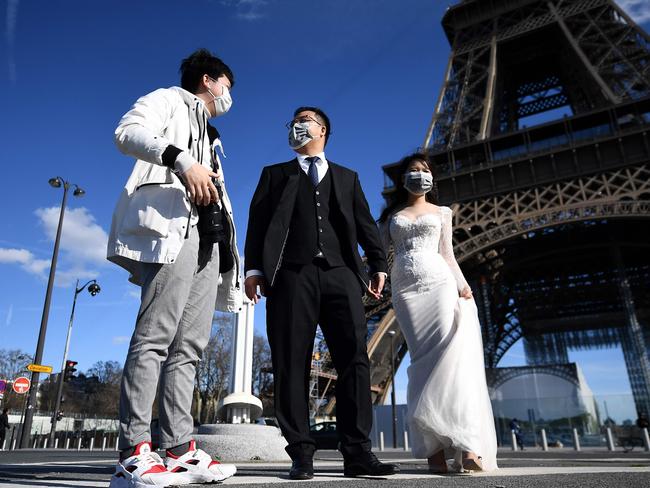 Vietnamese tourists wearing face masks and wedding clothes stand in front of the Eiffel Tower. Picture: AFP