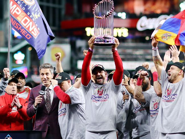 Manager Dave Martinez #4 of the Washington Nationals hoists the Commissioners Trophy after being thrown out of the sixth game of the series.