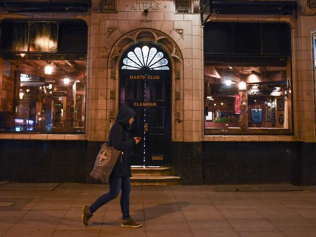 LONDON, ENGLAND - MARCH 20: A woman walks past an empty pub on March 20, 2020 in London, United Kingdom. British Prime Minister Boris Johnson announced that the country's bars, pubs, restaurants and cafes must close tonight to curb the spread of COVID-19, which has killed more than 100 people in the UK. (Photo by Peter Summers/Getty Images)