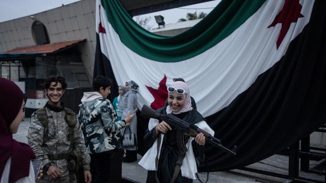 A woman poses for a photograph with a rebel fighter's gun in Umayyad Square in Damascus. Syria’s population finally felt free to dissent from the dominant narrative. Picture: Chris McGrath/Getty Images