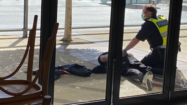 A man is restrained by a police officer at Rosebud Plaza. Picture: Supplied