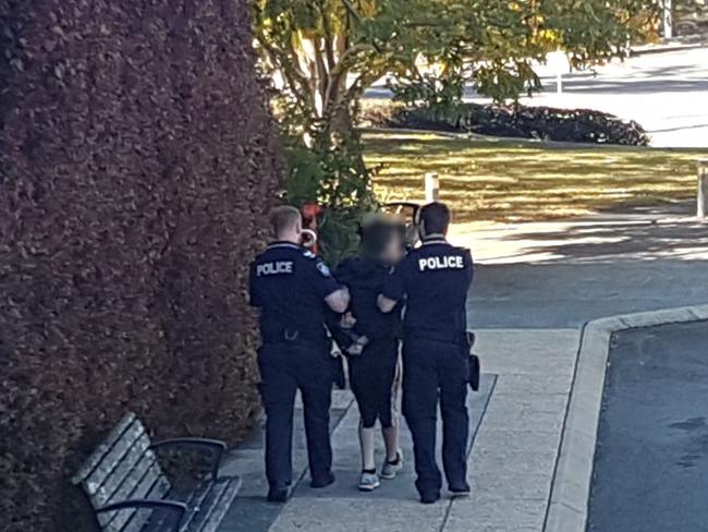 A teenager is led away by police after a brawl on the steps of Richlands Magistrates Court on Thursday.