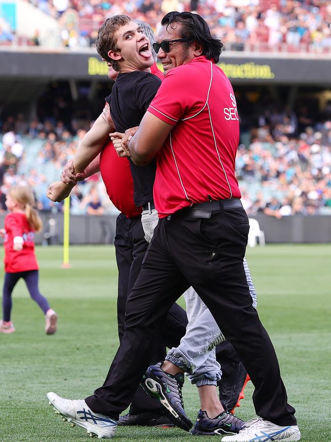 Pitch invader removed from the oval by security. (Photo by Sarah Reed/AFL Photos via Getty Images)