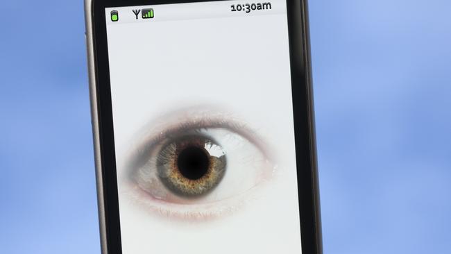 Privacy concept - an eye watching you from the touchscreen of a smartphone.