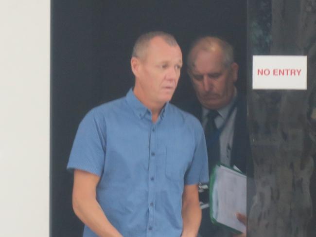 Mr Commane (front, blue shirt) leaving court after his first appearance. He will be excused from attending next time. Picture: NewsLocal