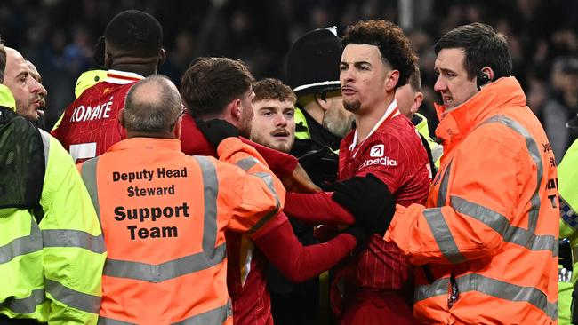 Liverpool's English midfielder #17 Curtis Jones is held back by stewards as he remonstrates with Everton players after the English Premier League football match between Everton and Liverpool at Goodison Park in Liverpool, north west England on February 12, 2025. The match ended in a draw at 2-2. (Photo by Paul ELLIS / AFP) / RESTRICTED TO EDITORIAL USE. No use with unauthorized audio, video, data, fixture lists, club/league logos or 'live' services. Online in-match use limited to 120 images. An additional 40 images may be used in extra time. No video emulation. Social media in-match use limited to 120 images. An additional 40 images may be used in extra time. No use in betting publications, games or single club/league/player publications. /