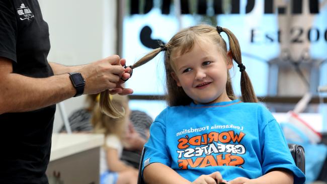 Cooper Pamment, 6, has his hair put in ponytails before getting cut. Picture: Robert Pozo