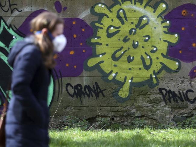 A woman walks past coronavirus-related graffiti in Edinburgh, Scotland. Picture: PA via AP