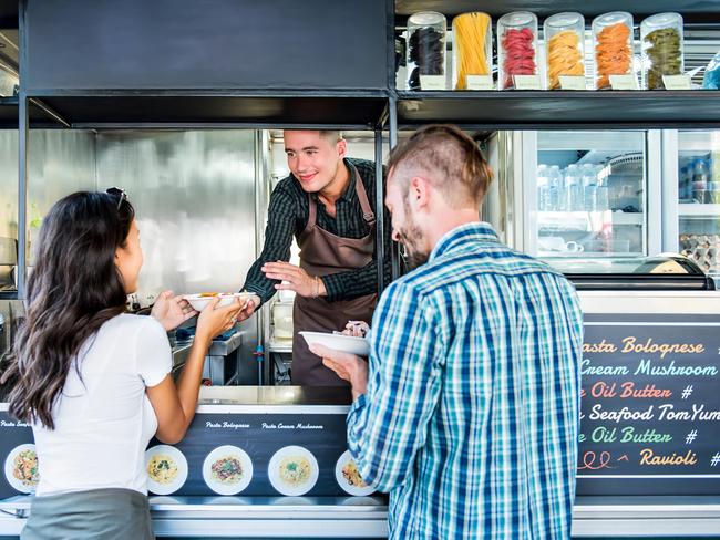 Tourist couple buying pasta from food truck at outdoor market. Food truck istock