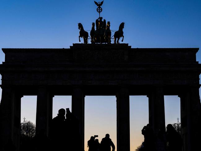 Tourists taking selfies are silhouetted against Berlin's Brandenburg Gate as it catches the last rays of sun. Picture: AFP