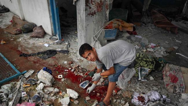 A Palestinian boy checks debris around a pool of blood at a UN school that had been turned into a shelter in Nuseirat, central Gaza. Picture: Bashar Taleb / AFP