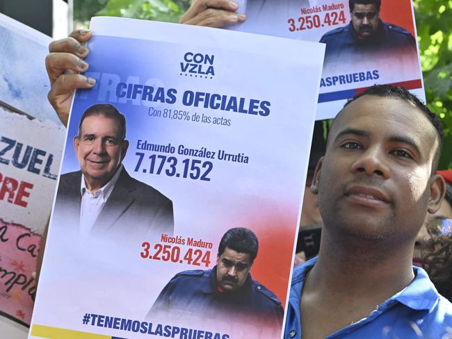 A man displays a banner with the results of Venezuela's July 28 presidential election, according to the opposition, as he gathers in support of Venezuelan opposition leader Edmundo Gonzalez Urrutia outside the Suarez and Reyes presidential residence in Montevideo on January 4, 2025. Edmundo Gonzalez Urrutia traveled to Uruguay on Saturday to meet with President Luis Lacalle Pou, following his meeting with Argentina's President Javier Milei, on a regional tour to drum up support ahead of President Nicolas Maduro's swearing-in for a third term. (Photo by Santiago Mazzarovich / AFP)