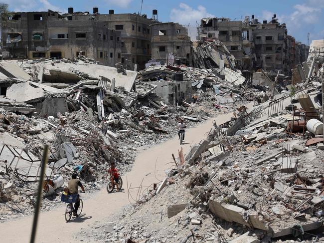 Palestinians cycle past destroyed buildings levelled in Beit Lahia, in the northern Gaza Strip. Picture: AFP