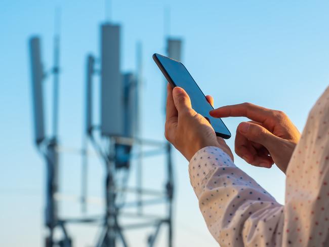 5G communications tower with man using mobile phone