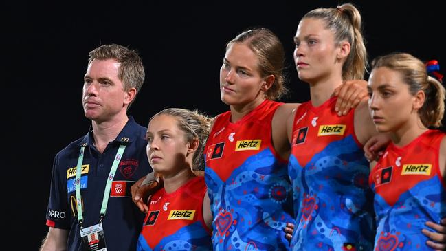 CAIRNS, AUSTRALIA - OCTOBER 24: Mick Stinear, Senior Coach of the Demons, lines up with players before the round nine AFLW match between Hawthorn Hawks and Narrm (Melbourne Demons) at Cazaly's Stadium, on October 24, 2024, in Cairns, Australia. (Photo by Albert Perez/AFL Photos via Getty Images)